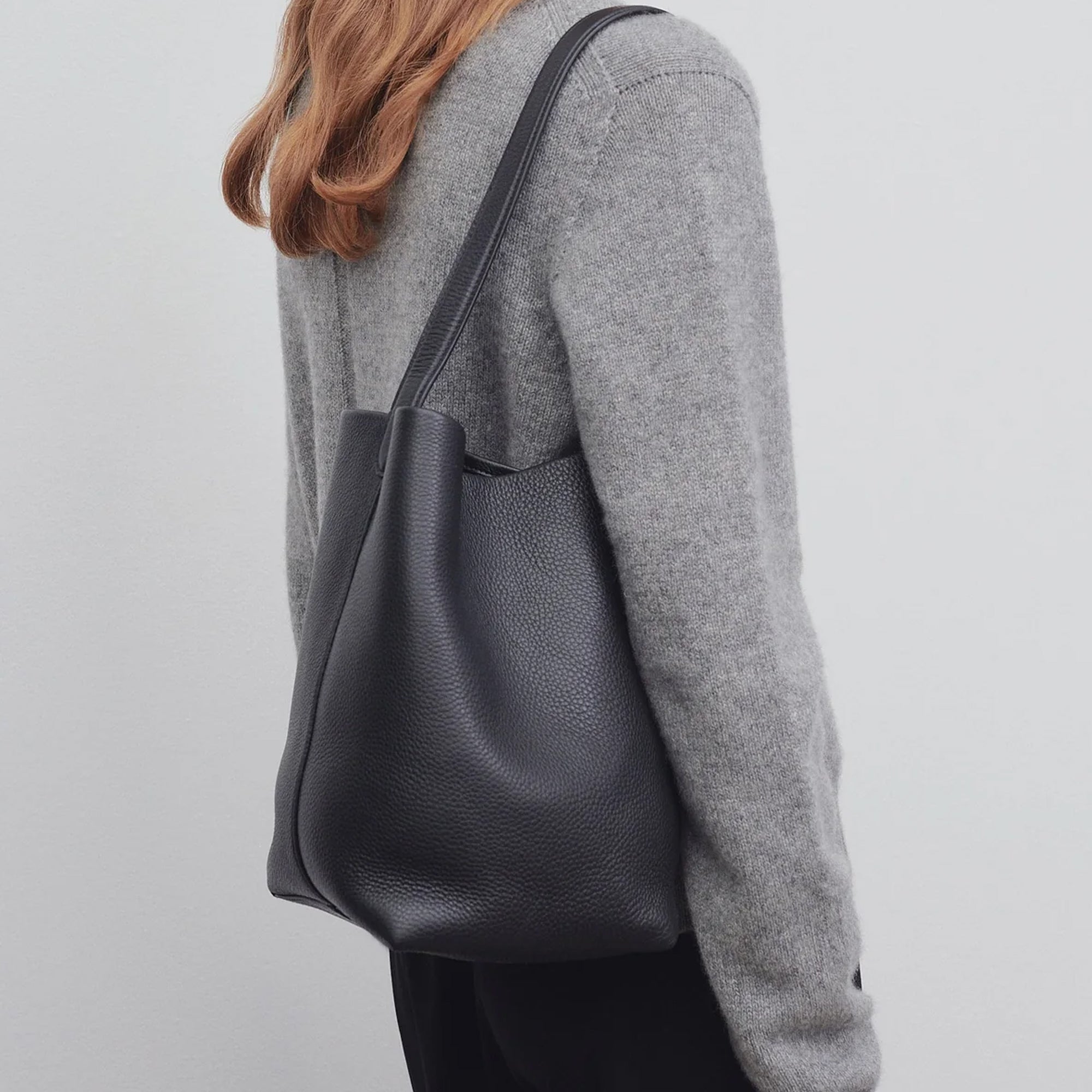 model with the natural grain and soft drape on a Park Tote inspired medium leather bag in black