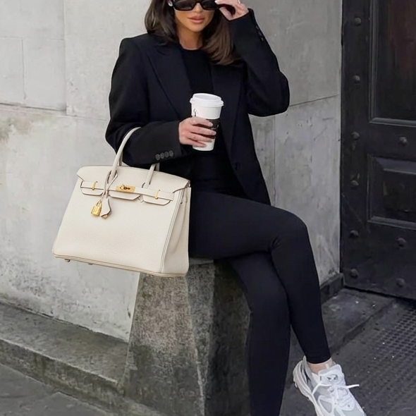 Model carrying the Leather 30 cream pebbled leather handbag with gold hardware