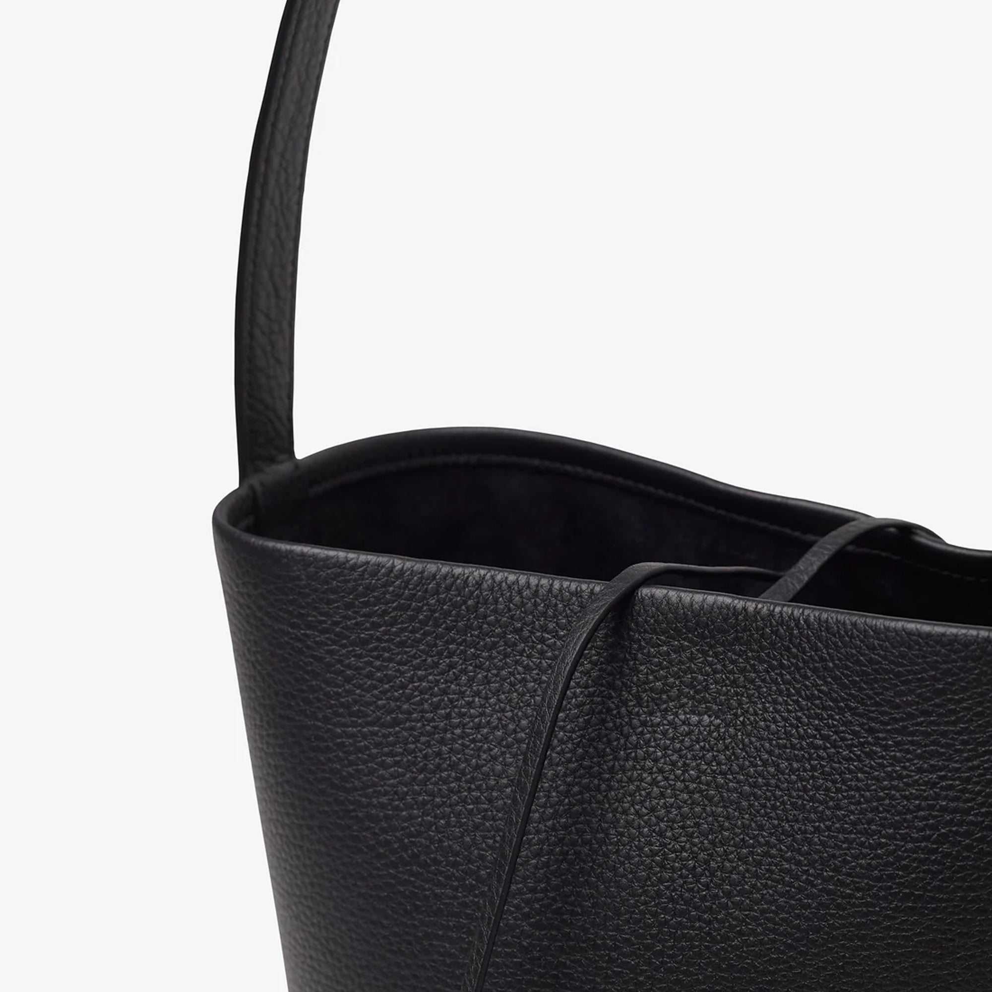 Detail view of the natural grain and soft drape on a Park Tote inspired medium leather bag in black