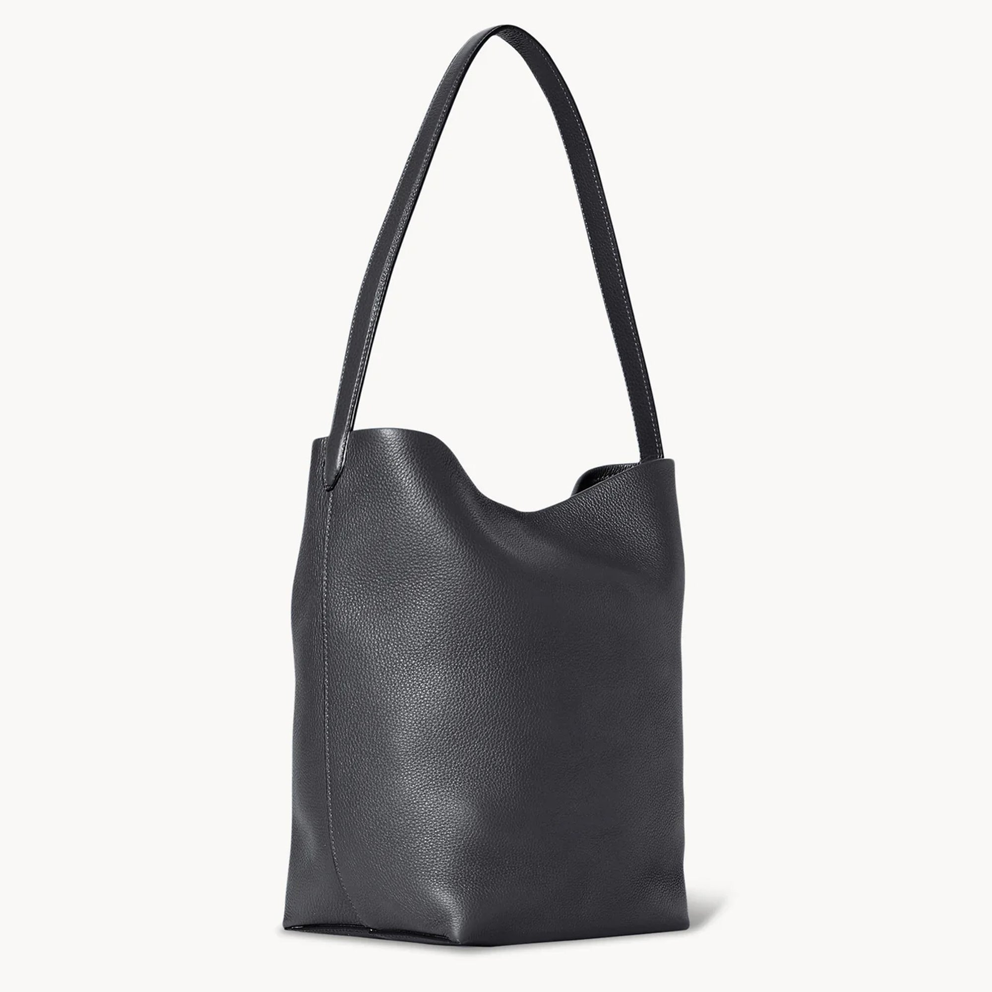 side view of natural grain and soft drape on a Park Tote inspired medium leather bag in black
