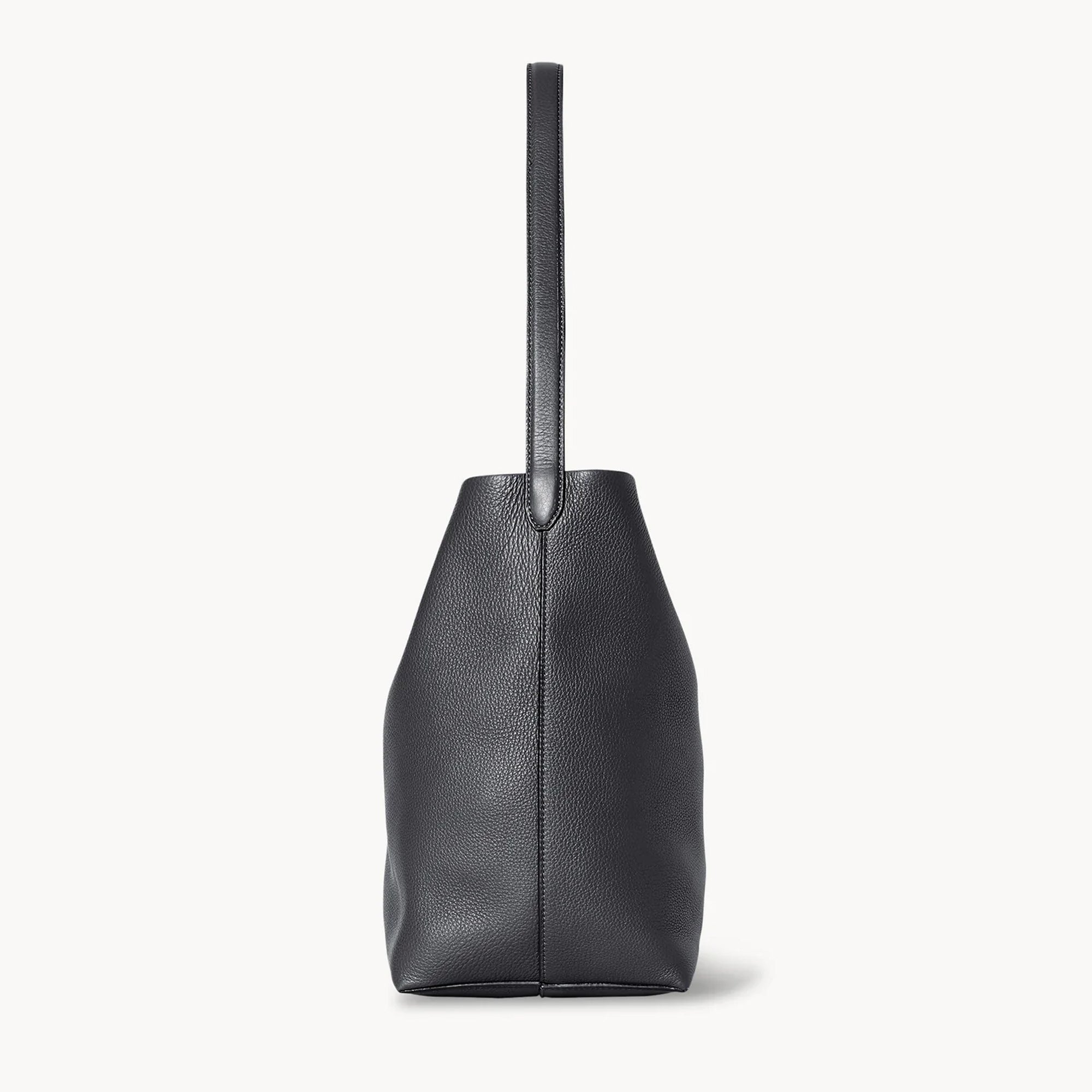 side view of natural grain and soft drape on a Park Tote inspired medium leather bag in black