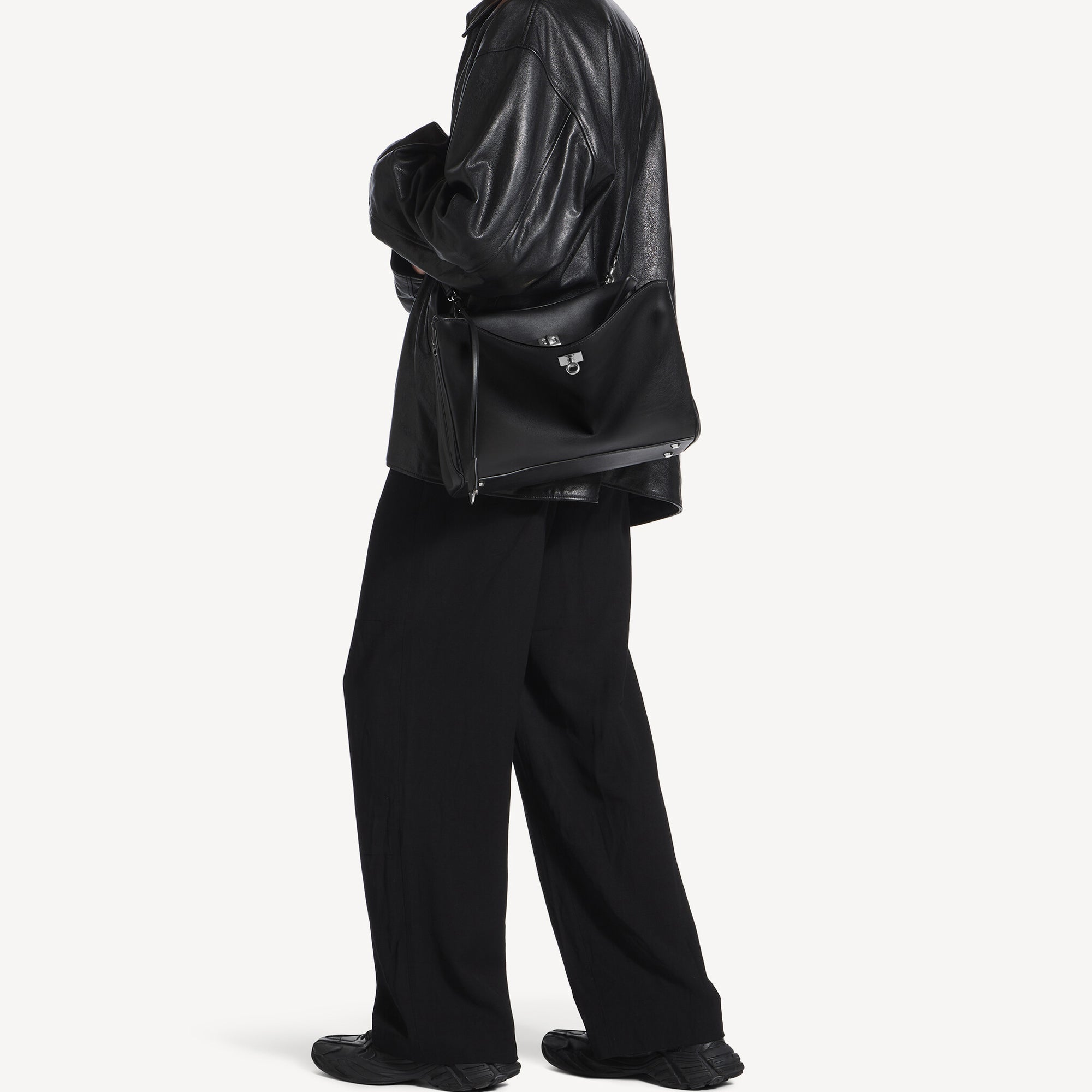 model wearing black slouchy medium tote bag with polished silver hardware and a relaxed rectangular shape.