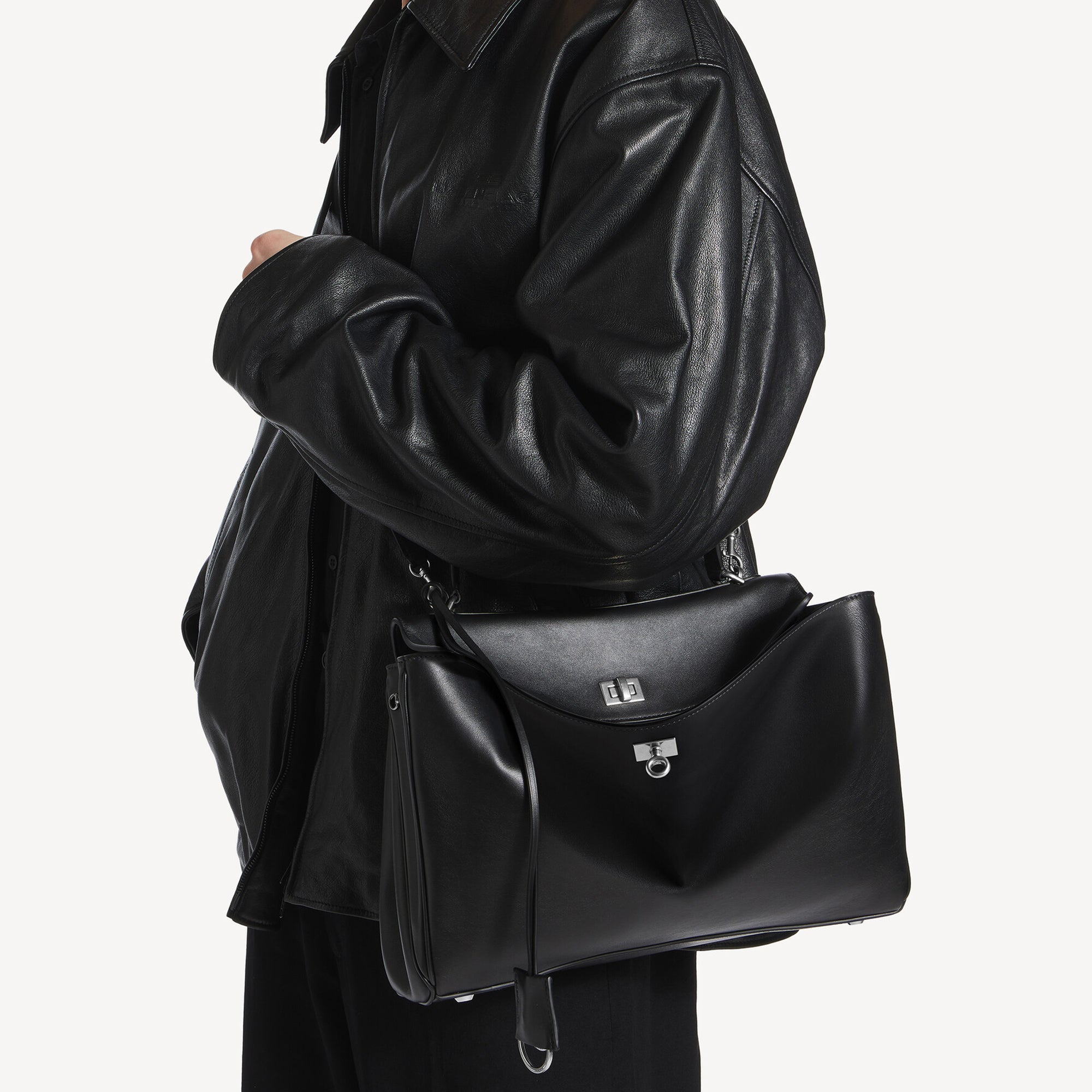 chic model wearing black slouchy medium tote bag with polished silver hardware and a relaxed rectangular shape.