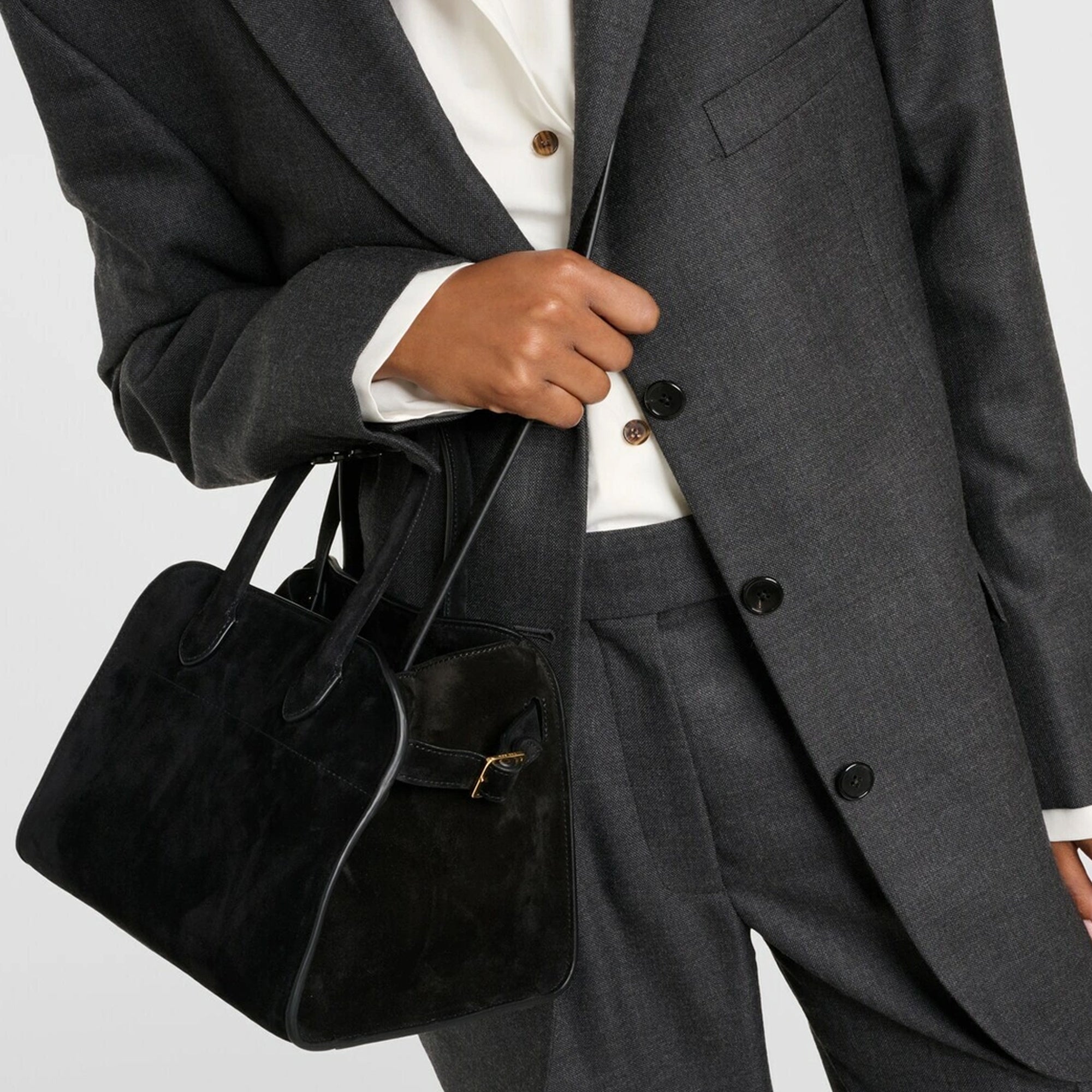 model with Margaux 10 style suede tote bag in black with belted side details.